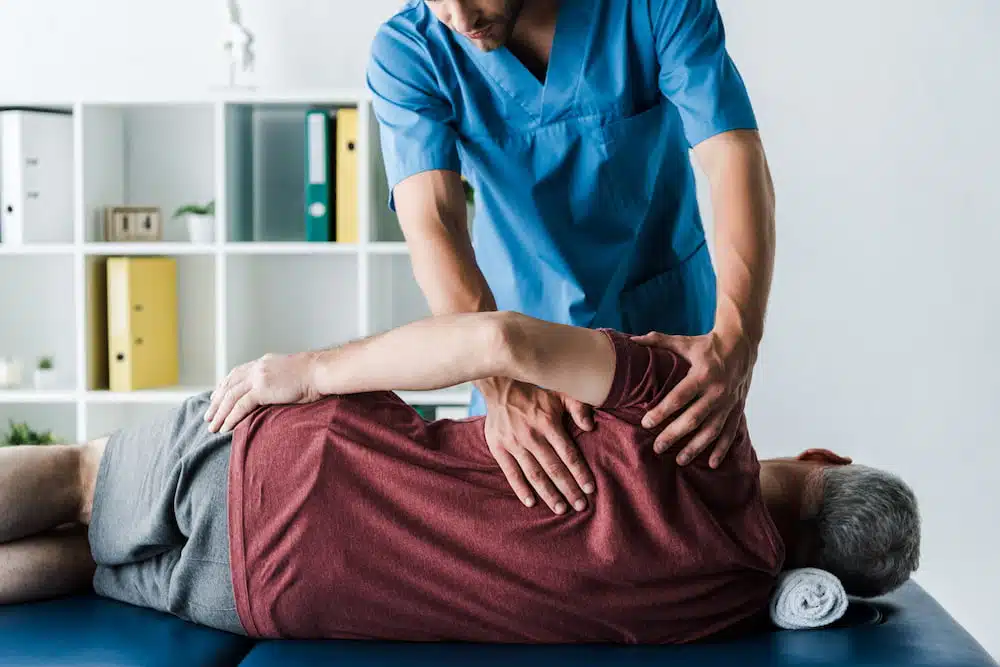 doctor assisting a middle aged man | chiropractic myths