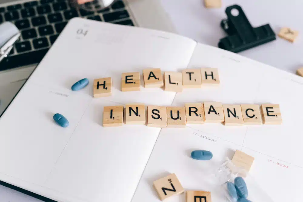 planner with scrabble pieces on top spelling health insurance